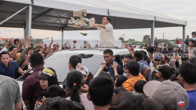 Calon presiden nomor urut 2 Prabowo Subianto membagikan baju kepada warga usai acara Masak Besar di Cilincing, Jakarta, Sabtu, (30/12/2023). [Suara.com/Alfian Winanto]