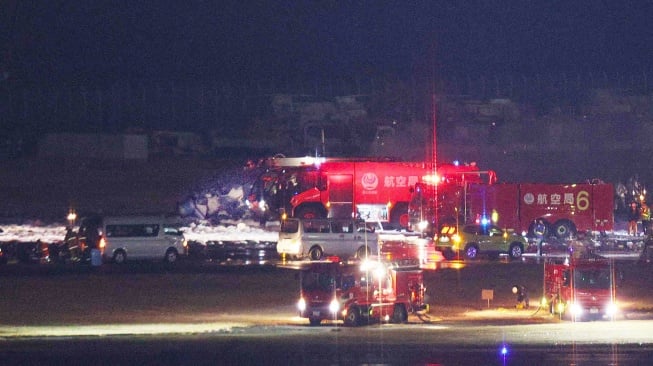 Petugas pemadam kebakaran berusaha memadamkan api di pesawat Japan Airlines yang terbakar di landasan Bandara Haneda, Tokyo, Jepang, Selasa (2/1/2024). [JIJI PRESS / AFP]