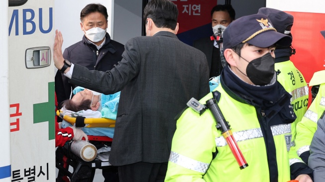 Petugas media mengevakuasi pemimpin partai oposisi Korea Selatan Lee Jae-myung setelah diserang saat konferensi pers di Busan, Korea Selatan, Selasa (2/1/2024). [YONHAP / AFP]