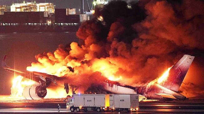 Penampakan pesawat Japan Airlines terbakar di landasan Bandara Haneda, Tokyo, Jepang, Selasa (2/1/2024). [JIJI PRESS / AFP]