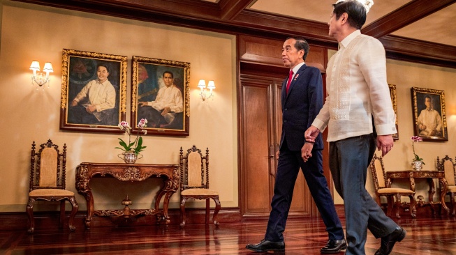 Presiden Indonesia Joko Widodo, bersama Presiden Filipina Ferdinand Marcos Jr. berjalan melewati foto para Presiden saat kunjungannya di Istana Malacanang, di Manila, Filipina, Rabu (10/1/2024). [Ezra Acayan/Pool/AFP]