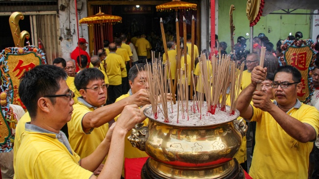 Warga keturunan Tionghoa menancapkan dupa saat melakukan prosesi pemindahan patung Dewa Kwan Kong ke gedung baru klenteng di Makassar, Sulawesi Selatan, Rabu (10/1/2024).  [ANTARA FOTO/Arnas Padda/aww]