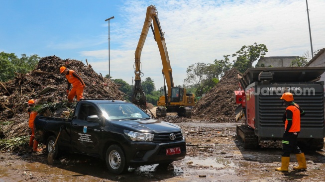 Ekskavator mengangkut sampah dari Kali Ciliwung ke mesin pencacah di tempat penyaringan sampah di TB Simatupang, Jakarta, Jumat (12/1/2024). [Suara.com/Alfian Winanto]