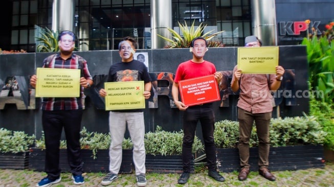 Aktivis dari Indonesia Corruption Watch (ICW)  menggelar aksi teaterikal menggunakan topeng Harun Masiku di depan gedung Merah Putih KPK, Jakarta, Senin (15/1/2024). [Suara.com/Alfian Winanto]