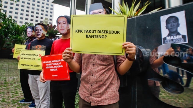 Aktivis dari Indonesia Corruption Watch (ICW)  menggelar aksi teaterikal menggunakan topeng Harun Masiku di depan gedung Merah Putih KPK, Jakarta, Senin (15/1/2024). [Suara.com/Alfian Winanto]