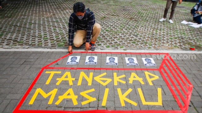 Aktivis dari Indonesia Corruption Watch (ICW) memasang selebaran bergambar Harun Masiku saat menggelar aksi teaterikal di depan gedung Merah Putih KPK, Jakarta, Senin (15/1/2024). [Suara.com/Alfian Winanto]