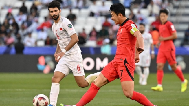 Gelandang timnas Korea Selatan #07 Son Heung-min menendang bola melewati gelandang Bahrain #06 Mohamed al-Hardan selama pertandingan pertama Grup E Piala Asia 2023 antara Korea Selatan vs Bahrain di Stadion Jassim bin Hamad di Doha pada 15 Januari 2024.HECTOR RETAMAL / AFP.