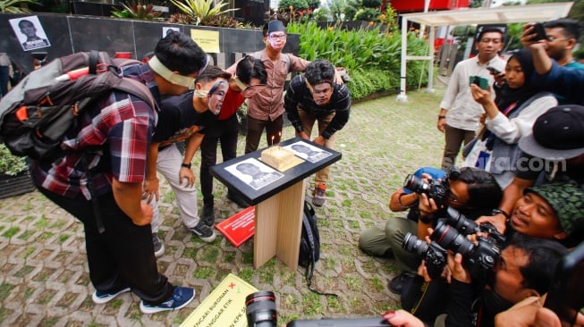 Aktivis dari Indonesia Corruption Watch (ICW)  menggelar aksi teaterikal menggunakan topeng Harun Masiku di depan gedung Merah Putih KPK, Jakarta, Senin (15/1/2024). [Suara.com/Alfian Winanto]