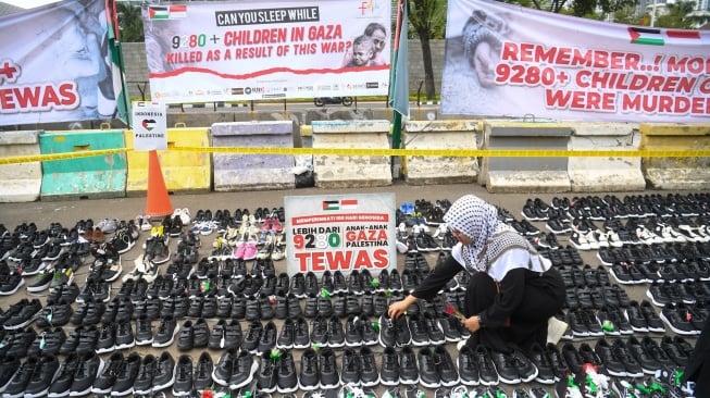 Seorang pengunjuk rasa meletakkan sepatu yang menyimbolkan tewasnya ribuan anak di Gaza saat aksi bela Palestina di depan Kedubes Amerika Serikat, Jakarta, Senin (15/1/2024). [ANTARA FOTO/Akbar Nugroho Gumay/rwa]