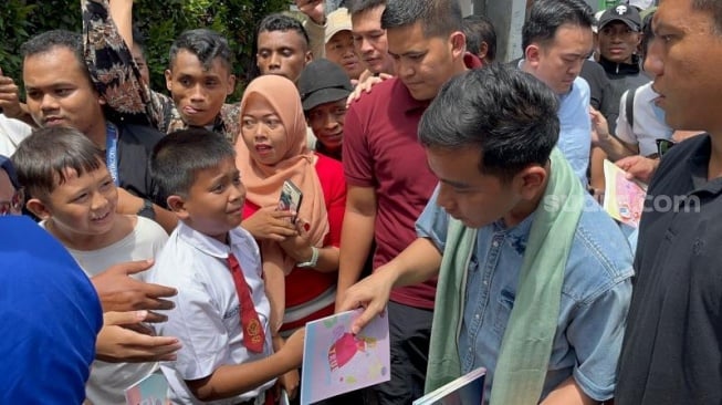 Gaya Gibran Kampanye di Kandang Anies, Kenakan Syal dan Bagi-bagi Buku