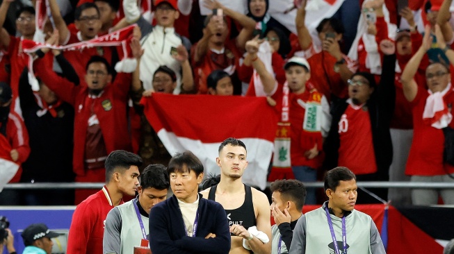 Pelatih Shin Tae-Yong (ketiga kiri) bersama para pemain timnas Indonesia berjalan melintasi lapangan pada akhir pertandingan sepak bola Grup D Piala Asia 2023 antara Indonesia dan Irak di Stadion Ahmad bin Ali di Al-Rayyan, Doha, Qatar, Senin (15/1/2024). [KARIM JAAFAR / AFP]