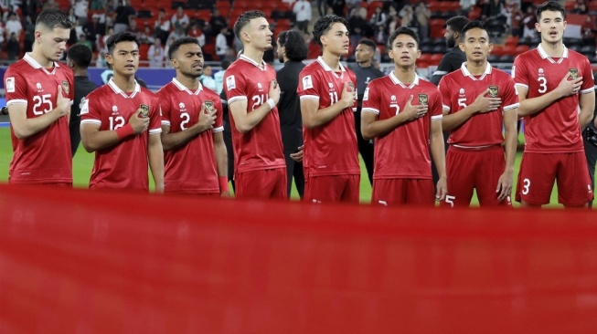 Para pemain Timnas Indonesia menyanyikan lagu kebangsaan Indonesia Raya pada laga Piala Asia 2023 kontra Irak di Stadion Ahmed bin Ali, Al Rayyan, Qatar, Senin (15/1/2024) malam WIB. [KARIM JAAFAR / AFP]