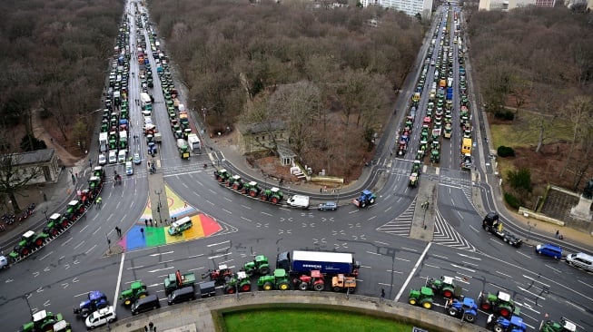 Traktor dan truk berbaris di dekat landmark gerbang Brandenburg saat berlangsungnya aksi protes para petani dan pengemudi truk di Berlin, Jerman, Senin (15/1/2024). [JOHN MACDOUGALL / AFP]