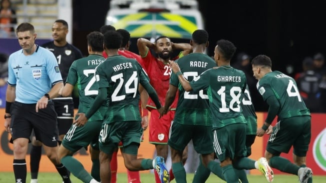 Wasit Shaun Evans (kiri) berjalan saat para pemain Arab Saudi melakukan selebrasi dalam pertandingan pertama Grup F Piala Asia 2023 antara Arab Saudi vs Oman di Stadion Internasional Khalifa di Doha pada 16 Januari 2024.KARIM JAAFAR / AFP.