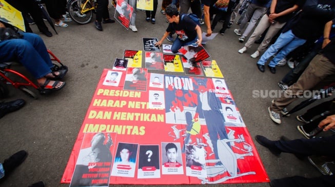 Aktivis memasang poster saat mengikuti aksi 17 Tahun Aksi Kamisan di depan Istana Negara, Jakarta, Kamis (18/1/2024). [Suara.com/Alfian Winanto]