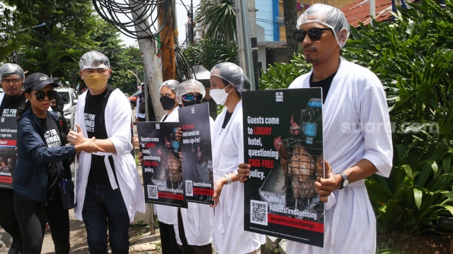 Sejumlah aktivis Act For Farmed Animals (AFFA) memakai jubah mandi sambil melakukan aksi di depan Hotel Aston Bellevue Radio Dalam, Senin (22/1/2024). [Suara.com/Alfian Winanto]