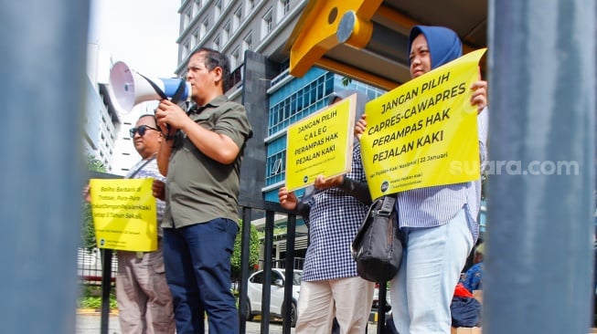 Aktivis dari Koalisi Pejalan Kaki menggelar aksi di Halte Tugu Tani, Jakarta, Senin (22/1/2024). [Suara.com/Alfian Winanto]