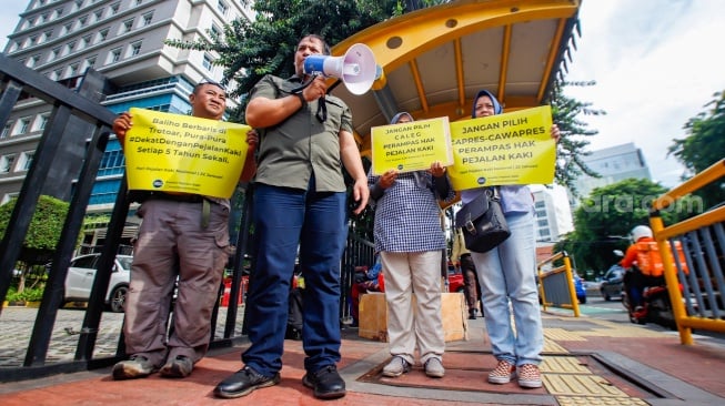 Aktivis dari Koalisi Pejalan Kaki menggelar aksi di Halte Tugu Tani, Jakarta, Senin (22/1/2024). [Suara.com/Alfian Winanto]