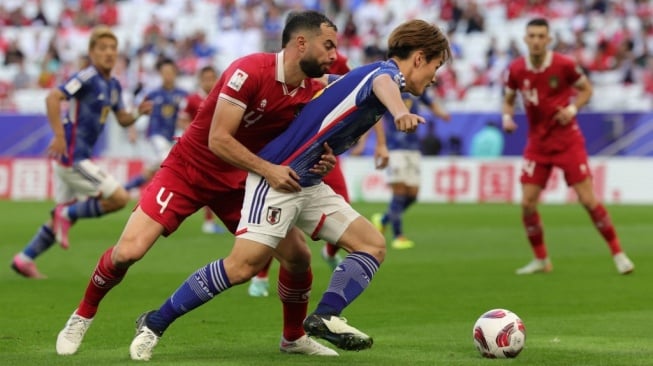 Bek Timnas Indonesia, Jordi Amat (kiri) menarik penyerang Jepang, Ayase Ueda pada laga Piala Asia 2023 di Stadion Al Thumama, Doha, Qatar, 24 Januari 2024. [Giuseppe CACACE / AFP]