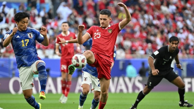 Gelandang Jepang Reo Hatate berebut bola dengan bek Indonesia Justin Hubner dalam laga Grup D Piala Asia 2023 yang digelar di Stadion al-Thumama, Doha, 24 Januari 2024.HECTOR RETAMAL / AFP