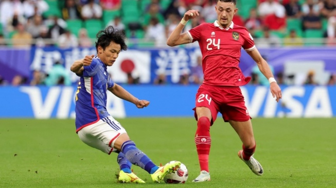 Gelandang timnas Jepang Reo Hatate dan gelandang timnas Indonesia Ivar Jenner berebut bola pada laga ketiga Grup D Piala Asia 2023 antara Timnas Jepang vs Indonesia di Stadion al Thumama Doha pada 24 Januari 2024. Giuseppe CACACE / AFP .