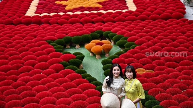 Seorang turis berswafoto di depan dupa yang disusun berbentuk bendera Vietnam di halaman desa Quang Phu Cau, Hanoi, Vietnam, Sabtu (20/1/2024). [Nhac NGUYEN / AFP] 