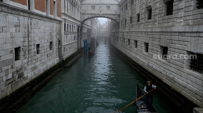 Seorang pengunjung mengenakan topeng dan kostum kuno berpose saat pra-pembukaan karnaval di Venesia, Italia, Sabtu (27/1/2024). [GABRIEL BOUYS / AFP] ​ 