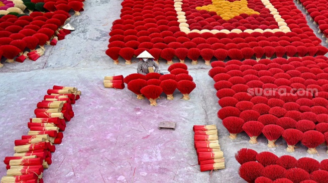 Seorang pekerja menyiapkan dupa di halaman desa Quang Phu Cau, Hanoi, Vietnam, Sabtu (20/1/2024). [Nhac NGUYEN / AFP] 