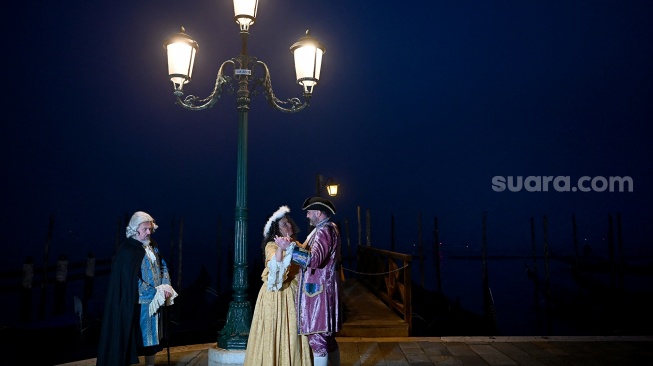 Seorang pengunjung mengenakan topeng dan kostum kuno berpose saat pra-pembukaan karnaval di Venesia, Italia, Sabtu (27/1/2024). [GABRIEL BOUYS / AFP] ​ 