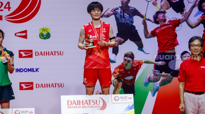 Pebulu tangkis Tunggal Putri Cina Wang Zhi Yi menunjukan medalinya usai menjuarai turnamen Indonesia Masters 2024 di Istora Senayan, Jakarta, Minggu (28/1/2024).  [Suara.com/Alfian Winanto]