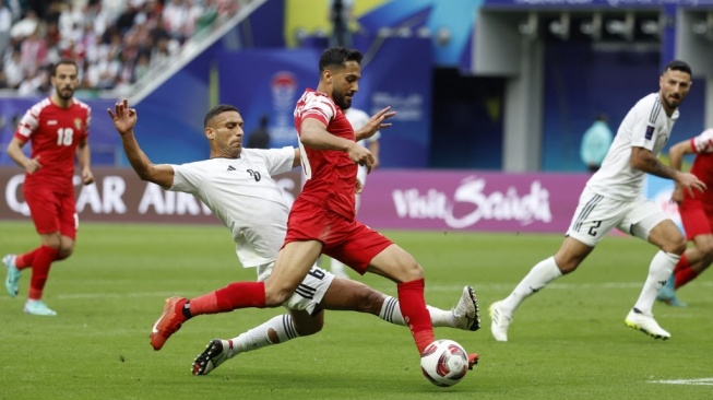 Gelandang Yordania Musa al-Tamari melewati bek Irak Ali Adnan dalam pertandingan 16 besar Piala Asia 2023 di Stadion Internasional Khalifa di Doha pada 29 Januari 2024.KARIM JAAFAR / AFP