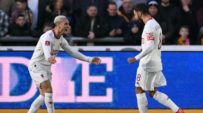 Gelandang Manchester United, Bruno Fernandes melakukan selebrasi dengan Antony usai mencetak gol pembuka timnya selama pertandingan putaran keempat Piala FA 2023-2024 antara Newport County vs Manchester United di Rodney Parade di Newport, Wales selatan pada 28 Januari 2024.JUSTIN TALLIS / AFP.