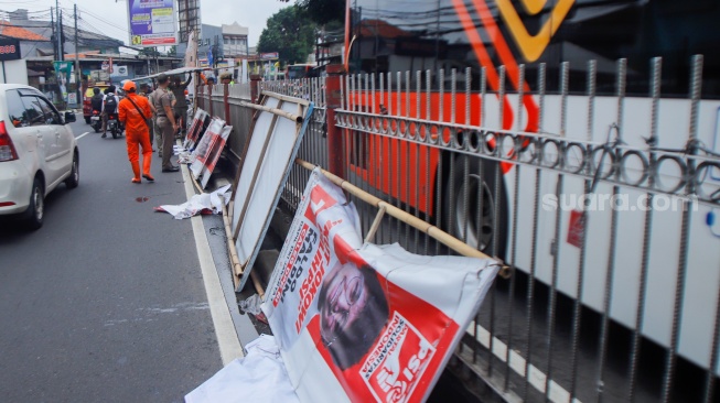 Petugas membongkar Alat Peraga Kampanye (APK) yang terpasang di Kawasan Kramat Jati, Jakarta, Senin (29/1/2024). [Suara.com/Alfian Winanto]