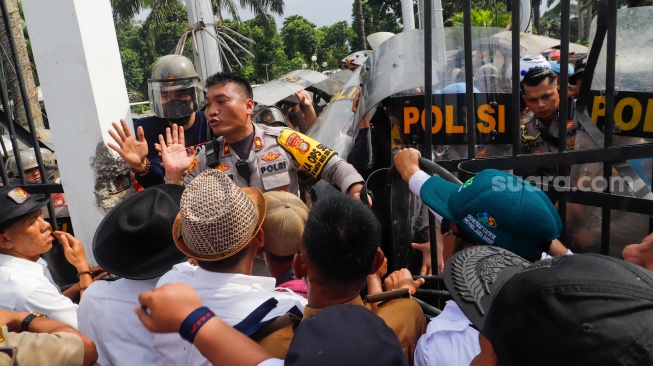 Massa Gabungan dari Kepala Desa se-Indonesia menerobos masuk kedalam usai menjebol pagar saat melakukan aksi di depan Gedung DPR RI, Jakarta, Rabu (31/1/2024). [Suara.com/Alfian Winanto]