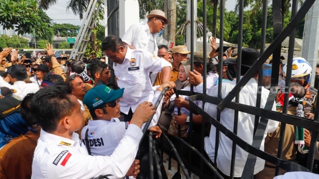 Massa Gabungan dari Kepala Desa se-Indonesia menerobos masuk kedalam usai menjebol pagar saat melakukan aksi di depan Gedung DPR RI, Jakarta, Rabu (31/1/2024). [Suara.com/Alfian Winanto]