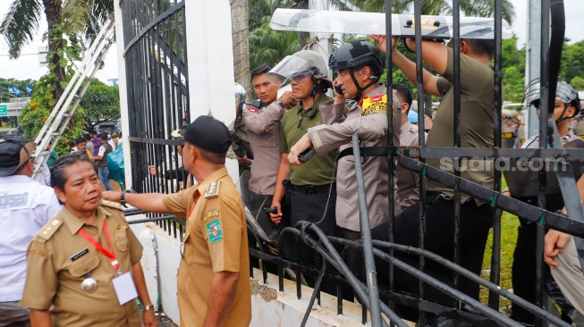 Massa Gabungan dari Kepala Desa se-Indonesia menerobos masuk kedalam usai menjebol pagar saat melakukan aksi di depan Gedung DPR RI, Jakarta, Rabu (31/1/2024). [Suara.com/Alfian Winanto]