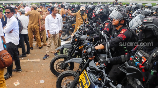 Massa Gabungan dari Kepala Desa se-Indonesia menghadang anggota Brimob saat melakukan aksi di depan Gedung DPR RI, Jakarta, Rabu (31/1/2024). [Suara.com/Alfian Winanto]