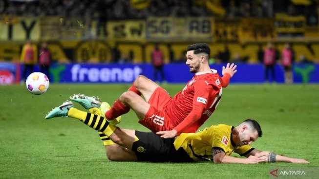 Penyerang Heidenheim Tim Kleindienst (kiri) ditekel bek Borussia Dortmund Niklas Suele pada pertandingan Liga Jerman di Heidenheim, Jumat (2/2/2024). (ANTARA/AFP/THOMAS KIENZLE)