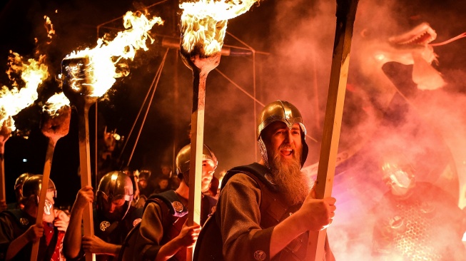 Anggota parade Up Helly Aa 'Jarl Squad' melintas sambil membawa obor saat Festival Up Helly Aa di Lerwick, Kepulauan Shetland, Skotlandia, Selasa (30/1/2024). [ANDY BUCHANAN / AFP]