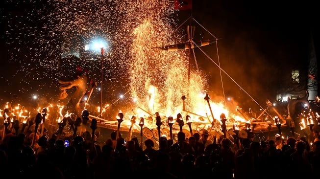 Anggota Up Helly Aa 'Jarl Squad' membakar kapal saat Festival Up Helly Aa di Lerwick, Kepulauan Shetland, Skotlandia, Selasa (30/1/2024). [ANDY BUCHANAN / AFP] 