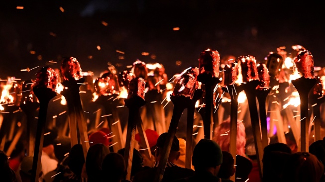 Anggota parade Up Helly Aa 'Jarl Squad' melintas sambil membawa obor saat Festival Up Helly Aa di Lerwick, Kepulauan Shetland, Skotlandia, Selasa (30/1/2024). [ANDY BUCHANAN / AFP] 