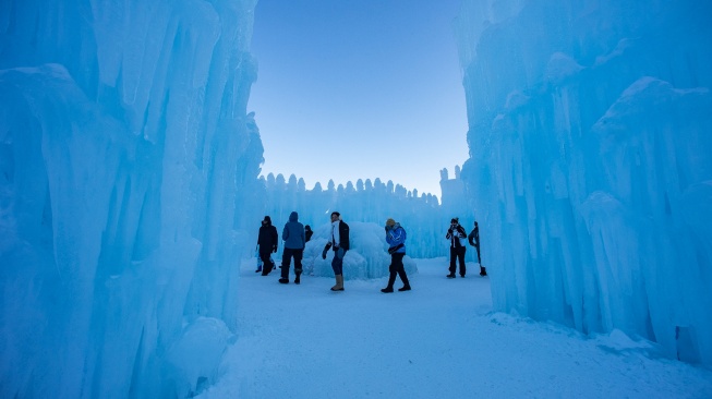 Orang-orang menjelajahi Ice Castles di North Woodstock, New Hampshire, Amerika Serikat, Kamis (1/2/2024). [Joseph Prezioso / AFP]