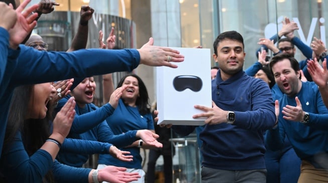 Aarish Syed, pelanggan pertama yang membeli headset Apple Vision Pro, keluar dari Apple Store dengan pembeliannya di New York City, Amerika Serikat, Jumat (2/2/2024). [ANGELA WEISS / AFP]