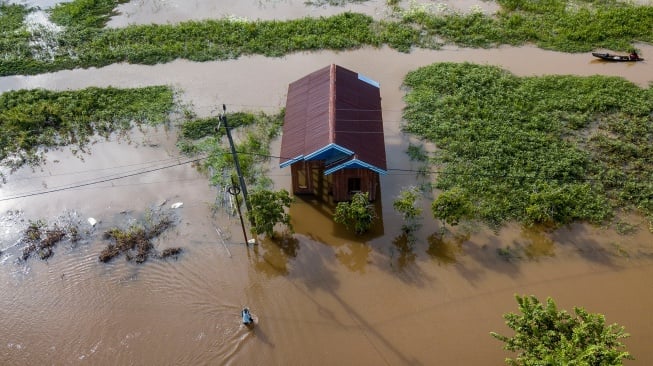 Foto udara seorang warga berjalan menerobos banjir akibat luapan Sungai Batanghari di Gedong Karya, Muaro Jambi, Jambi, Sabtu (3/2/2024). [ANTARA FOTO/Wahdi Septiawan/rwa]