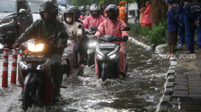 Kendaraan melintasi genangan banjir di Jalan DI Panjaitan, Jakarta, Senin (5/2/2024). [Suara.com/Alfian Winanto]