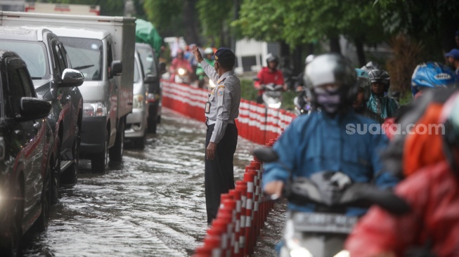 Kendaraan melintasi genangan banjir di Jalan DI Panjaitan, Jakarta, Senin (5/2/2024). [Suara.com/Alfian Winanto]