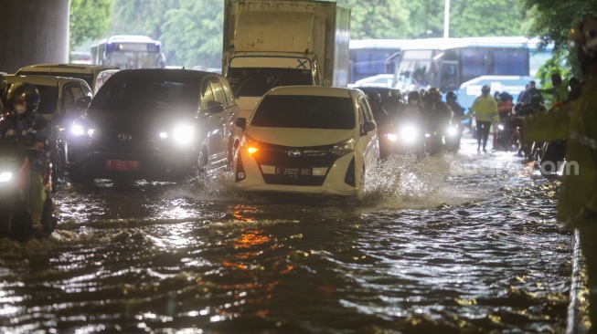 Kendaraan melintasi genangan banjir di Jalan DI Panjaitan, Jakarta, Senin (5/2/2024). [Suara.com/Alfian Winanto]