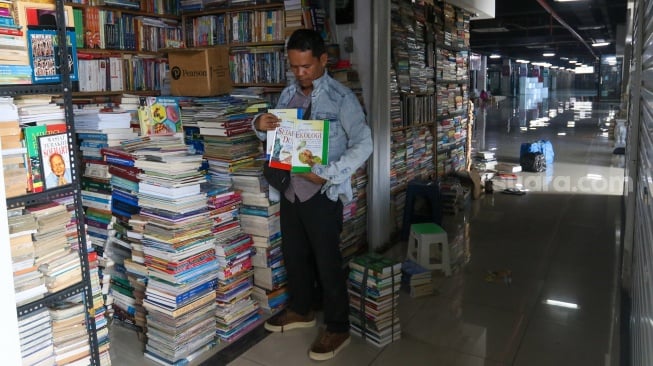 Pedagang merapikan buku jualannya di Sentra Buku Pasar Kenari, Jakarta, Senin (5/2/2024). [Suara.com/Alfian Winanto]