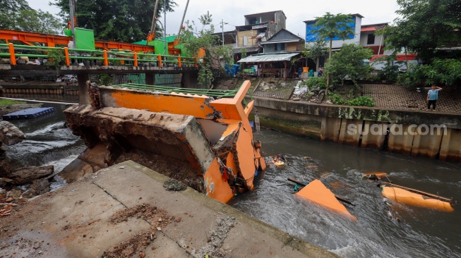 Warga melihat pos pantau Pintu Air Palmerah yang rubuh di Palmerah, Jakarta, Selasa (6/2/2024). [Suara.com/Alfian Winanto]