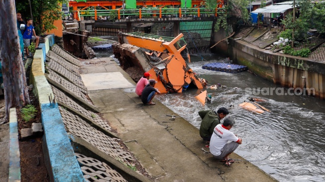 Warga melihat pos pantau Pintu Air Palmerah yang rubuh di Palmerah, Jakarta, Selasa (6/2/2024). [Suara.com/Alfian Winanto]